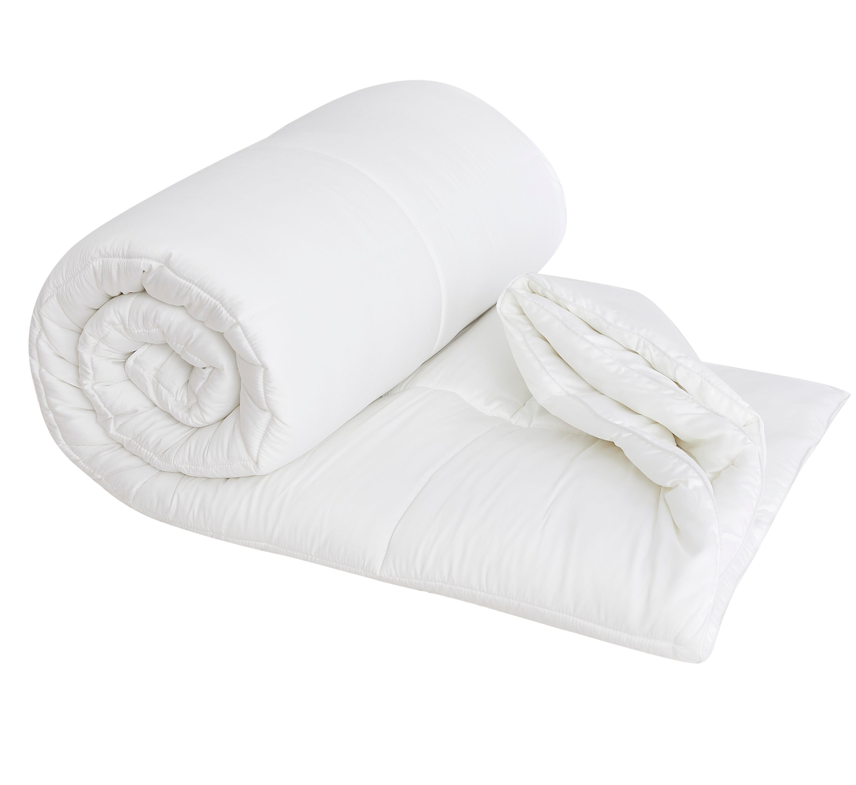 White rolled comforter partially unrolled on a flat surface, showcasing its soft texture.